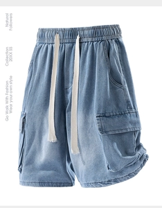 Detail of light blue washed denim cargo shorts with elastic waist and large side pockets