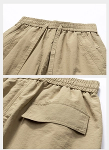 Detail of khaki trousers featuring elastic waistband with drawstring and flap pocket stitching