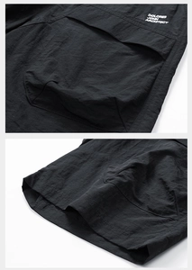 Detail of waterproof nylon cargo shorts featuring large utility pocket and brand lettering