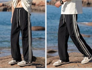 Dettaglio dei pantaloni casual neri con strisce laterali bianche e coulisse in vita