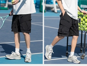 Close-up of black cargo shorts with large 3D pockets on a tennis court background