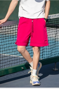 Dettaglio dei pantaloncini sportivi rosso rosa con coulisse da uomo su un campo da tennis