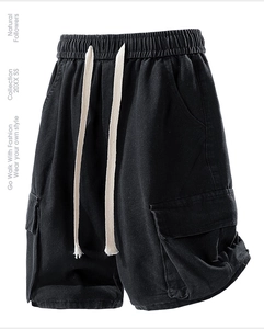 Detail of black cargo shorts featuring large flap pockets and a beige drawstring waist