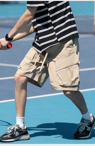 Detail of khaki cargo shorts with side pockets and adjustable drawstring waist in outdoor setting