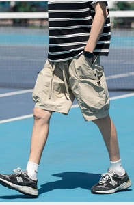Detail of khaki techwear shorts with drawstring waist and multi-pocket utility design