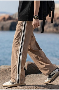 Dettaglio macro dei pantaloni casual marroni con striscia laterale logata sul tessuto