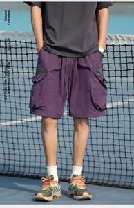 Detail of purple cargo shorts with large side pockets on a male model at a tennis court