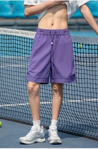 Dettaglio di pantaloncini sportivi viola con vita elastica su sfondo di campo da tennis