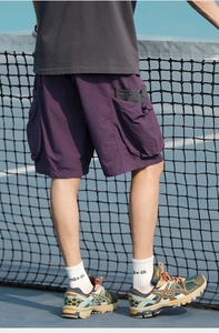 Close-up of purple cargo shorts with utility pockets and drawstring on tennis court