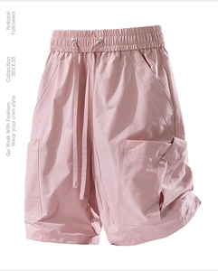 Detail view of light pink cargo shorts featuring elastic waist and utility pockets