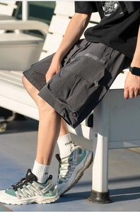 Detail view of dark grey cargo shorts featuring utility pockets with metal buckle straps