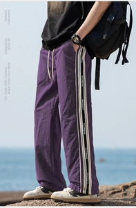 Dettaglio dei pantaloni casual viola con strisce laterali e coulisse su rocce all'aperto
