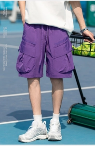 Detail view of purple cargo shorts featuring large side pockets on an outdoor tennis court