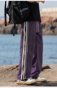 Dettaglio dei pantaloni viola con strisce laterali e coulisse sulla costa rocciosa