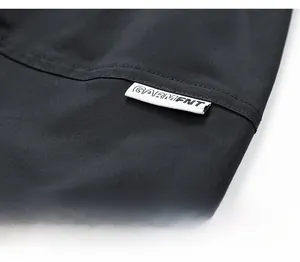 Close-up of black cargo shorts waist detail with white woven brand label and stitching