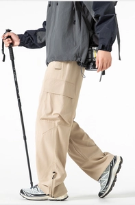 Dettaglio dei pantaloni cargo kaki con tasche laterali e orlo con zip regolabile