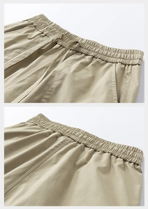 Detail of light khaki cargo shorts featuring elastic drawstring waist and reinforced pockets