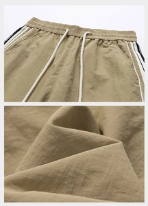 Dettaglio dei pantaloncini kaki con coulisse, strisce laterali e trama in twill