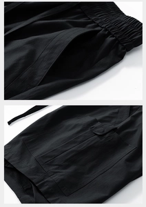Close-up of elastic drawstring waist and cargo flap pocket on black casual shorts