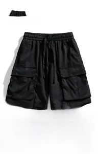 Detail of waterproof black cargo shorts featuring elastic drawstring waist and large utility pockets
