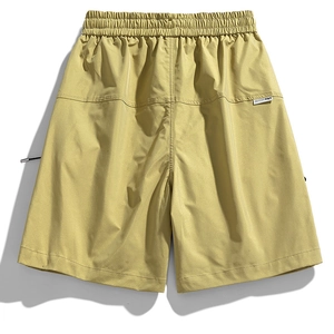 Detail view of mustard yellow cargo shorts with elastic waist and white woven logo label