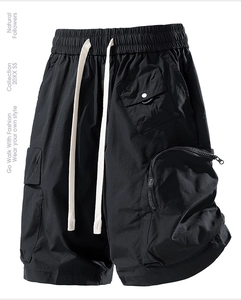 Detail of cargo shorts featuring elastic waist, white drawstring, and functional zip pockets