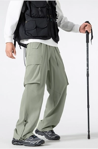 Dettaglio dei pantaloni cargo verde salvia con ampie tasche a patta e zip funzionale fondo