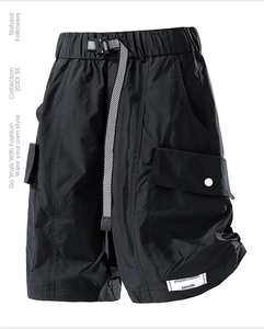 Detail of black tactical cargo shorts featuring a buckle belt and large flap side pockets