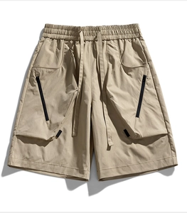 Detail of khaki cargo shorts featuring elastic drawstring waist and large zipper pockets