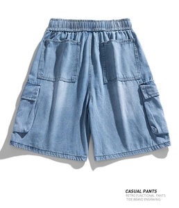 Detail of light blue washed denim cargo shorts with elastic drawstring and large utility pockets