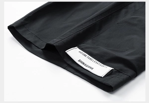 Detail of water-repellent fabric and trendy white logo label on black utility shorts
