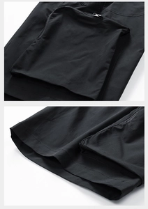 Detailed macro view of black cargo shorts featuring a zipper pocket and double stitching