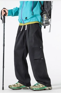 Detail of black outdoor cargo pants featuring functional flap pockets and white drawstring