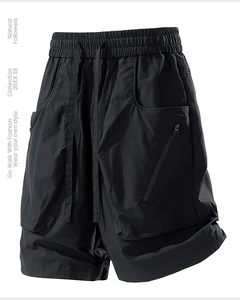 Detail of black techwear shorts showing elastic drawstring waist and large 3D cargo pockets