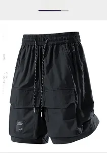 Dettaglio dei pantaloncini cargo neri con elastico in vita, coulisse e ampie tasche laterali