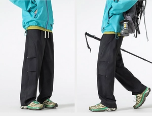 Detail of black Gorpcore cargo pants featuring 3D utility pockets and drawstring waist