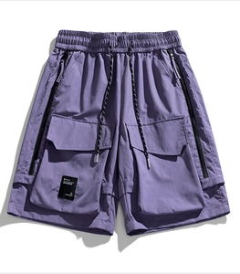 Dettaglio dei pantaloncini cargo viola con elastico in vita e tasche laterali con zip