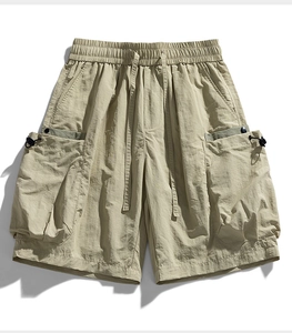 Macro shot of khaki techwear cargo shorts showing adjustable drawstring and pocket texture