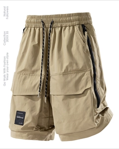 Dettaglio dei pantaloncini cargo kaki con coulisse in vita e tasche con zip laterali