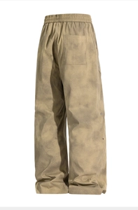 Detail view of khaki washed trousers showing elastic waist and metallic side snaps