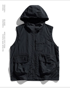Détail macro du gilet fonctionnel noir à capuche avec grandes poches tactiques
