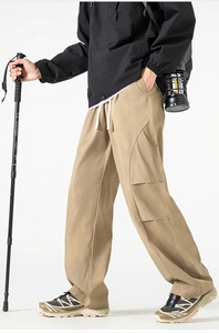 Detail of khaki cargo pants featuring elastic drawstring waist and 3D utility pockets