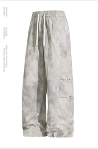 Detail of grey tie-dye wide-leg trousers with elastic waistband and decorative buttons