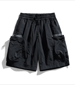 Detail of black cargo shorts featuring adjustable drawstring waist and contrast pocket trim