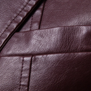 Detailed macro view of dark burgundy faux leather jacket with textured grain and stitching