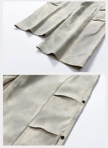 Detail of cargo pants showing the neat hem stitching and side flap pocket with metal button