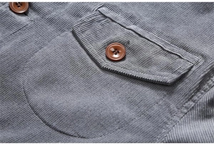 Detailed close-up of grey corduroy jacket fabric texture and pocket button detail