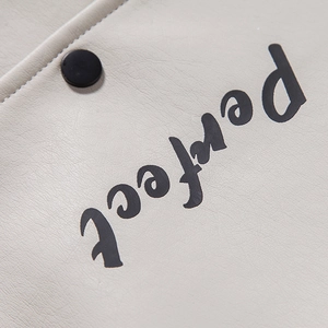 Detail of white faux leather jacket with Perfect print and black metal button closure