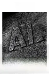 Macro shot of 3D embossed AL lettering on black lychee grain faux leather jacket material