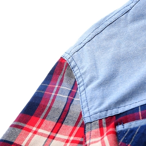 Detail of blue denim stitching joined with red and blue plaid flannel fabric on shirt